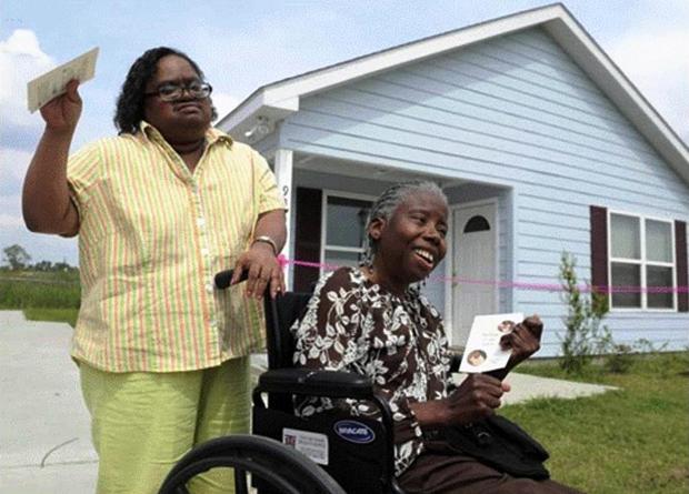 Woman with man in a wheelchair outside of a home