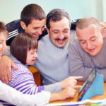 Supported Decision Making - group of happy people with disability having fun with tablet